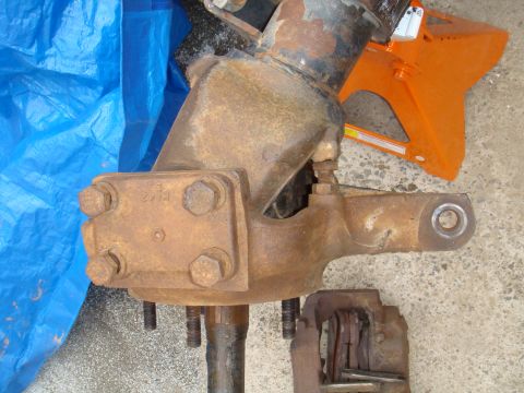 1992 Ford Bronco - Close-up of a heavily rusted vehicle axle assembly, showing a brake caliper and part of a jack stand.