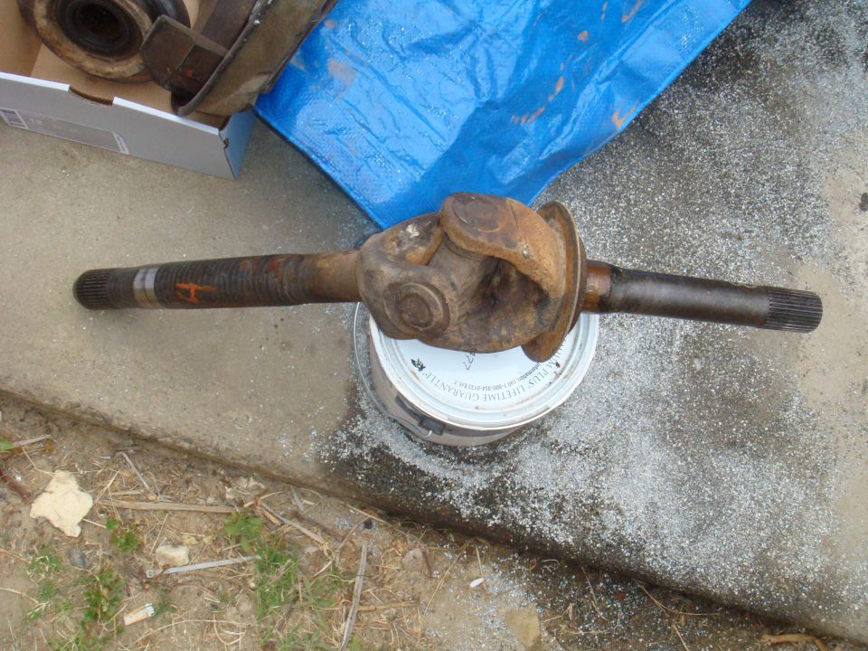 Rusty driveshaft with U-joint sitting on a can
