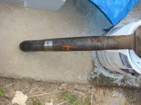 1992 Ford Bronco - An axle shaft is shown resting on concrete, with a paint can and blue tarp in the background.