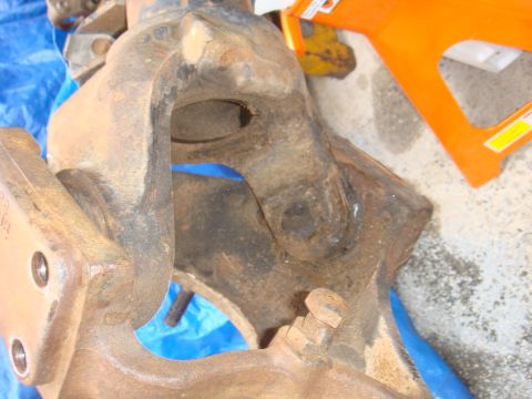 1992 Ford Bronco - Close-up view of a heavily rusted metal component, likely a vehicle suspension part, with visible bolts and openings.