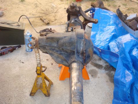 1992 Ford Bronco - A front axle assembly is supported by jack stands, with a toolbox, spray can, and beer bottle on the ground.