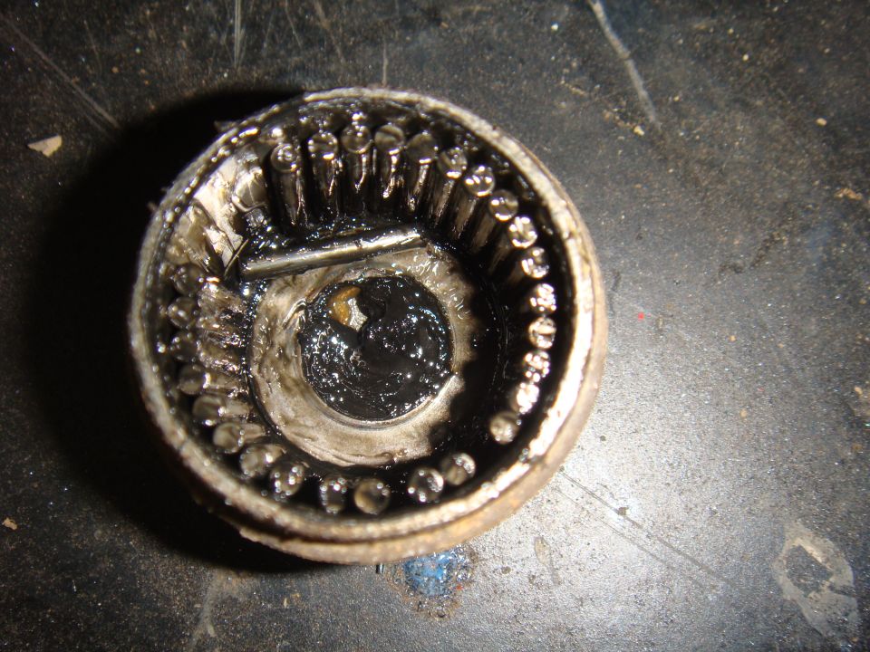 Close-up of a heavily greased and worn wheel bearing with visible roller bearings and internal components
