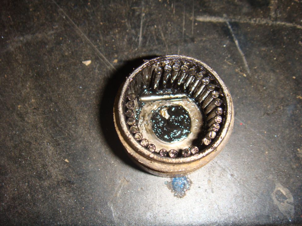 Differential pinion gear assembly with rollers and grease on a dark surface