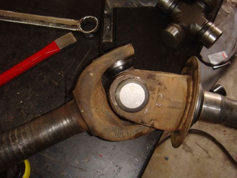 1992 Ford Bronco - Close-up of a rusty driveshaft universal joint with a wrench and pry bar nearby.