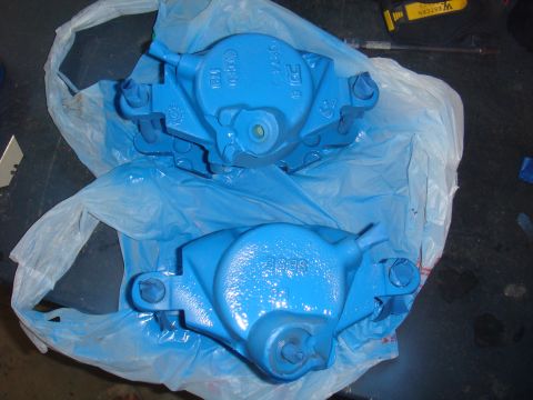 1992 Ford Bronco - Two freshly painted blue brake calipers are laid out on blue plastic sheeting.