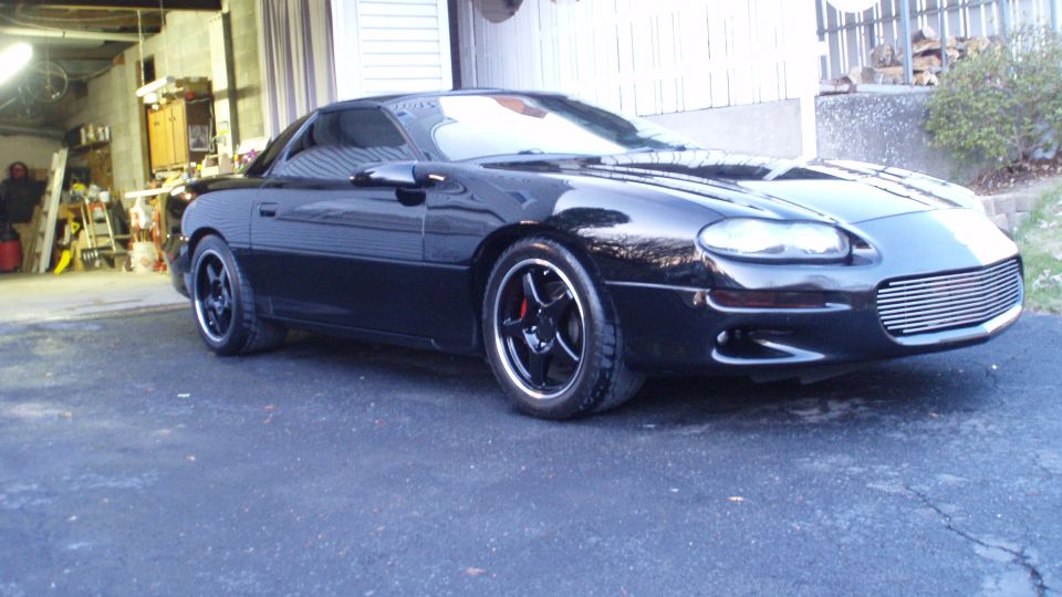 Black 2002 Chevrolet Camaro parked outside a garage, showing its front quarter view and aftermarket grille
