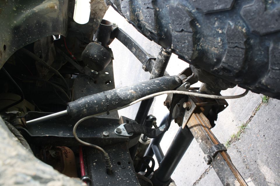 Vehicle front suspension with large tire, shock absorber, and leaf spring visible