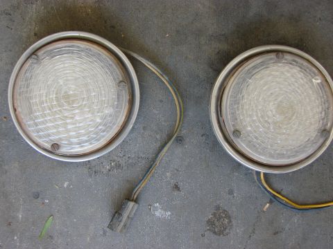 1978 Ford Bronco - Two clear round vehicle lights with visible wiring and connectors are shown against a concrete surface.