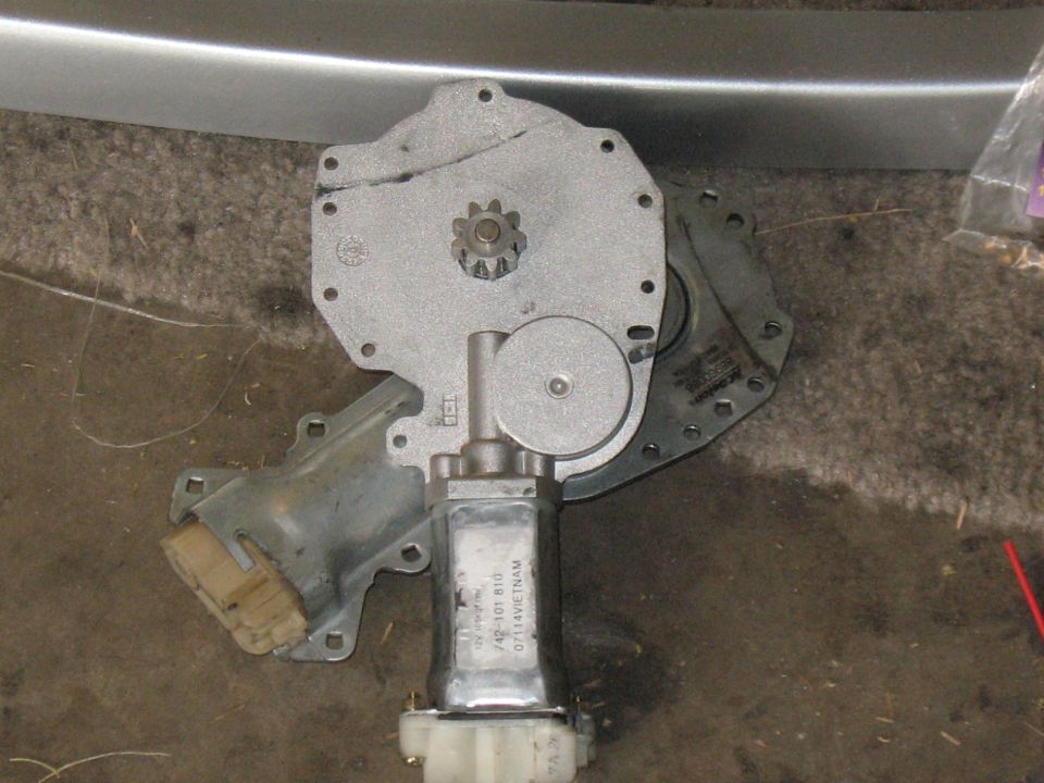 Power window regulator motor with exposed pinion gear on concrete garage floor