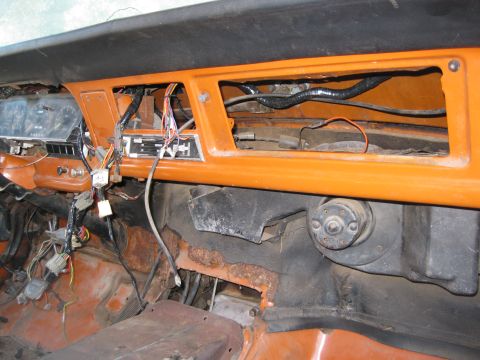 1969 Ford F-250 - The dashboard and floor of a truck show extensive wiring and rust damage, indicating a need for repair.