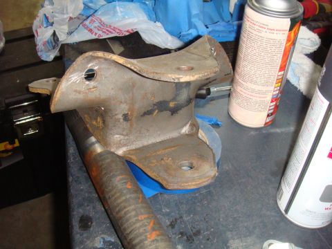 1992 Ford Bronco - A close-up view of a rusty metal bracket and axle shaft, likely a vehicle part, on a workbench.