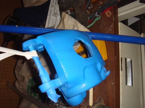 1992 Ford Bronco - A freshly painted brake caliper sits on a workbench, ready for reassembly.
