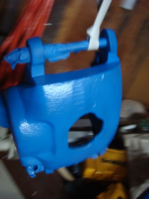 1992 Ford Bronco - A blue painted brake caliper is shown, suspended by a strap, with tape applied to its mounting points.