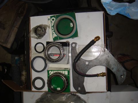 1992 Ford Bronco - Parts laid out on a box: brake caliper bracket, bearings, and seals.