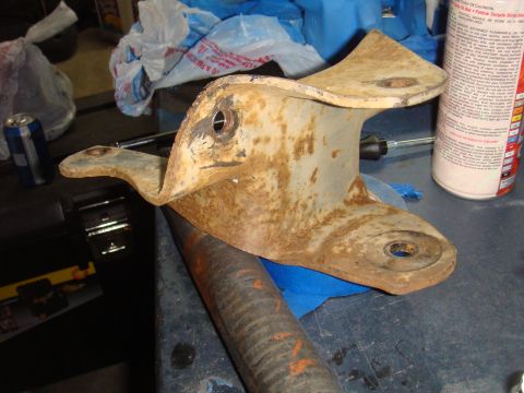 1992 Ford Bronco - A heavily rusted metal bracket sits on a workbench, possibly a spare part.