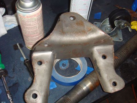 1992 Ford Bronco - A metal bracket sits on a workbench next to a can of spray paint and blue masking tape.