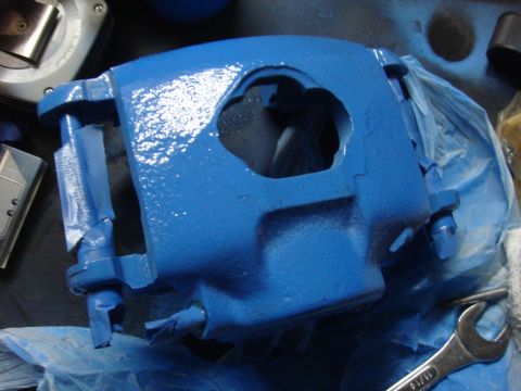 1992 Ford Bronco - A blue painted brake caliper is shown on a workbench, partially covered by plastic sheeting.