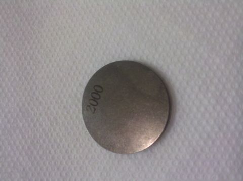 1992 Ford Taurus - A metal disc with the number 2000 stamped on it is shown against a textured background.