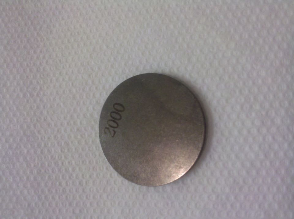 Metal disc stamped with '2000'