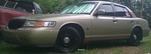 2000 Mercury Grand Marquis - Gold 2000 Mercury Grand Marquis with black grille and wheels, parked next to a red pickup truck.