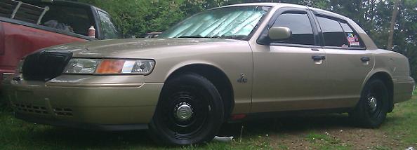 Gold 2000 Mercury Grand Marquis parked next to a red pickup truck
