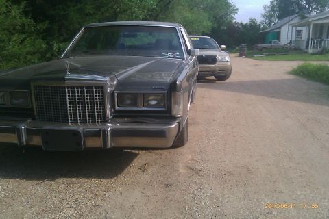 2000 Mercury Grand Marquis - A vintage Lincoln Town Car is parked on a dirt road, with another car visible behind it.