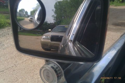 2000 Mercury Grand Marquis - Side mirror view of a 2000 Mercury Grand Marquis parked on a dirt road.