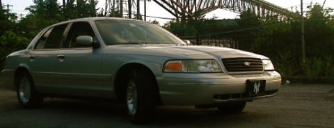 2000 Ford Crown Victoria - A silver sedan is parked outdoors, with a bridge structure visible overhead.