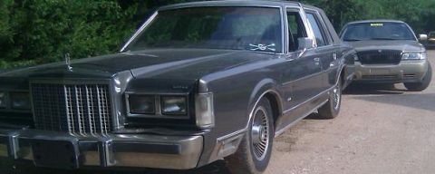 2000 Mercury Grand Marquis - A dark gray Lincoln Town Car is parked on a dirt road, with a gold Mercury Grand Marquis behind it.