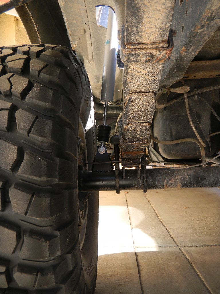 Close-up of a large off-road tire and rusty leaf spring suspension on a vehicle's rear axle