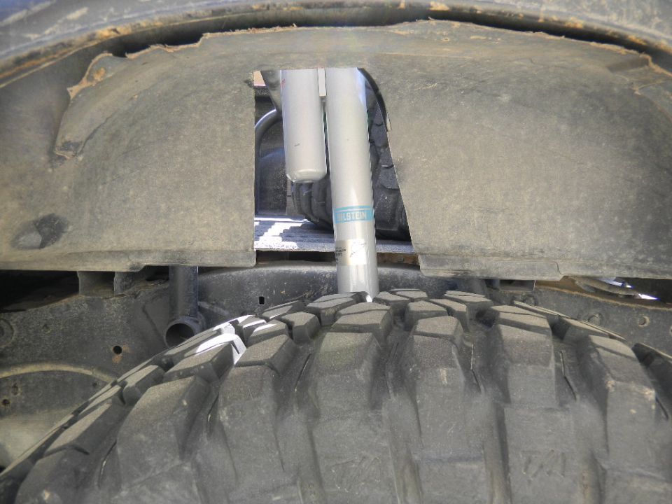 Close-up of a Bilstein shock absorber in a vehicle's wheel well, with a large tire tread visible