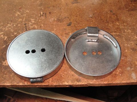 1995 Ford Bronco - Two metal caps, one with a welded bracket, sit on a wooden surface.