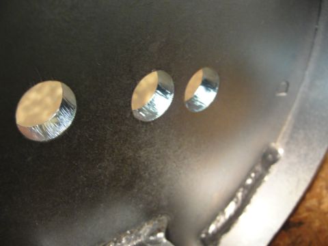 1995 Ford Bronco - A close-up view of a metal part with three circular openings and evidence of welding.