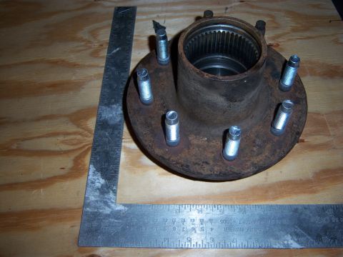 1996 Ford Bronco - A rusty wheel hub assembly with studs is shown on a wooden surface next to a ruler.