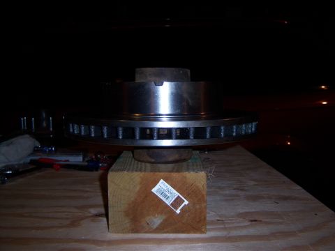 1996 Ford Bronco - A brake rotor is shown resting on a wooden block, with tools visible in the background.