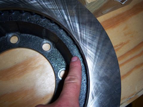1996 Ford Bronco - Close-up of a worn brake rotor, showing the surface texture and a finger indicating wear.