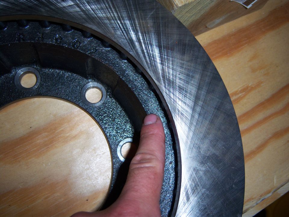 Brake rotor with visible wear marks, finger pointing to the edge