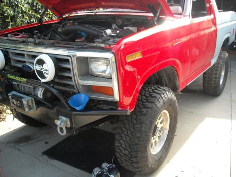 1985 Ford Bronco - Front view of a modified 1980s Ford Bronco with the hood up, revealing the engine bay.