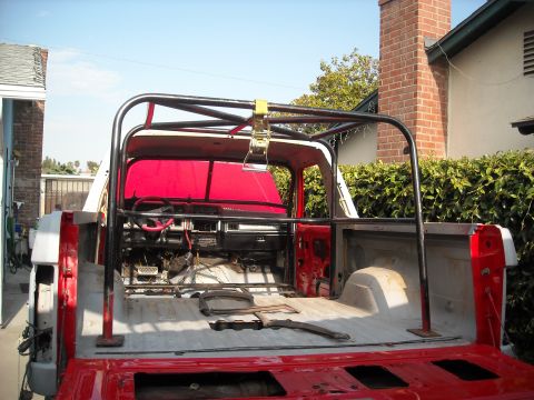 1985 Ford Bronco - The interior and bed of a vehicle are shown with a custom roll cage installed, ready for off-road modification.