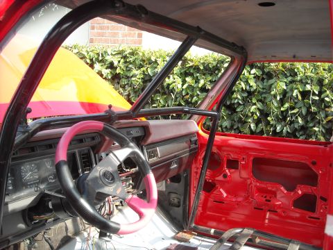 1985 Ford Bronco - Custom roll cage installed in the interior of a truck, showing the dashboard and open hood.