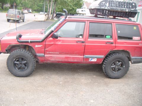 1998 Jeep Cherokee - This red Jeep Cherokee is equipped with a snorkel and a large cargo box on its roof rack.