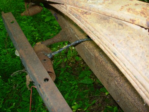 1976 Ford Bronco - Close-up of heavily rusted vehicle leaf springs and frame components.