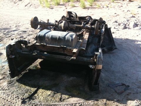 1987 Suzuki Samurai - The frame, axles, and fuel tank of a vehicle are visible, suggesting it has been stripped or severely damaged.