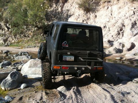 1987 Suzuki Samurai - This 1987 Suzuki Samurai navigates a rocky, off-road trail, showing its rear profile and custom license plate.