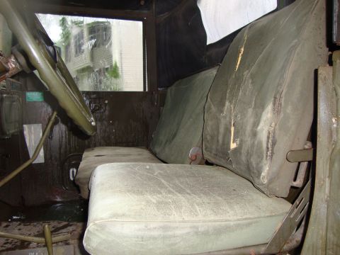 1970 Jeep Commando - The interior of a utilitarian vehicle, likely a military truck, with worn fabric seats and a functional dashboard.
