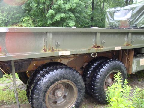 1970 Jeep Commando - A side view of a military truck's bed and dual rear wheels, with visible rust on the bed frame and large, treaded tires.