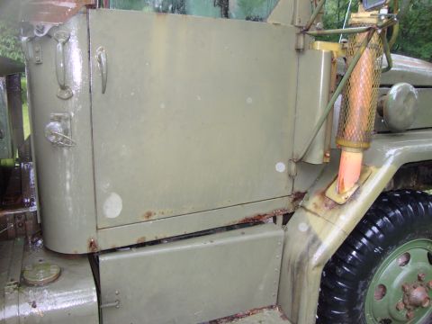 1970 Jeep Commando - Detail of a weathered military truck's side panel and wheel well, showing rust.