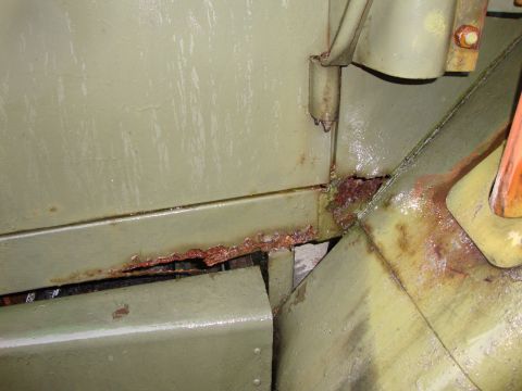 1970 Jeep Commando - Close-up view of extensive rust compromising the structural integrity of a vehicle's metal panel and hinge.