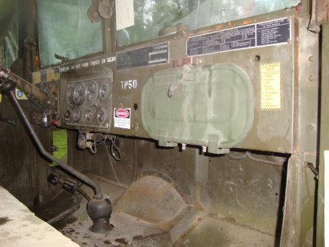 1970 Jeep Commando - Dashboard of a military truck shows gauges, a large green storage compartment, and various warning labels.