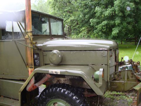 1970 Jeep Commando - This military truck is parked outdoors on a rainy day, with trees in the background.